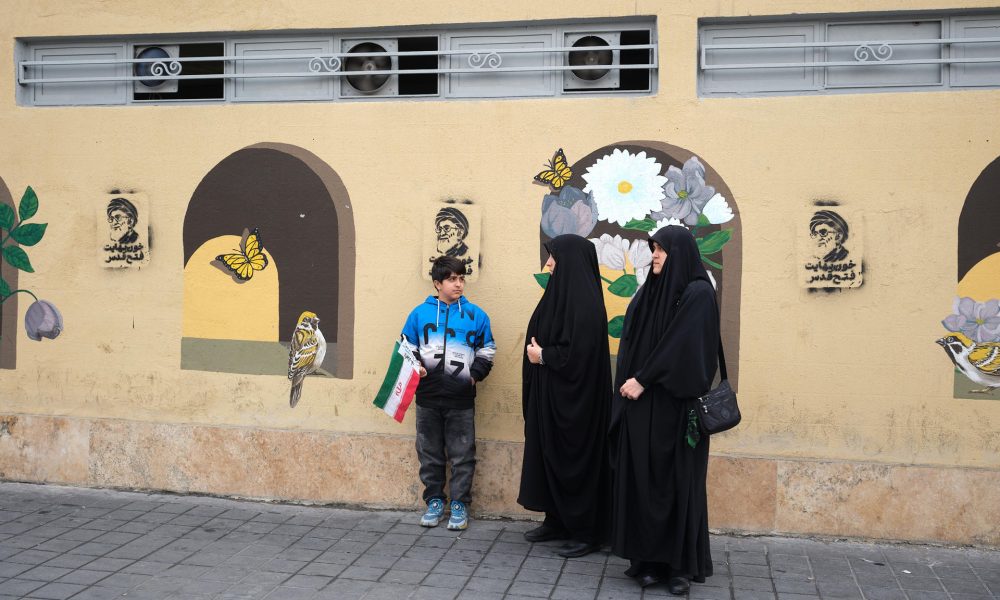 Un grupo de personas esperan frente a grafitis del asesinado líder supremo de Irán Alí Jameneí en las inmediaciones de la plaza Engelab (Revolución) de Teherán. Desde su muerte el 28 de febrero en ataques de Estados Unidos e Israel, las calles de Teherán se han llenado de grafitis, carteles y murales con su retrato. EFE/Jaime León