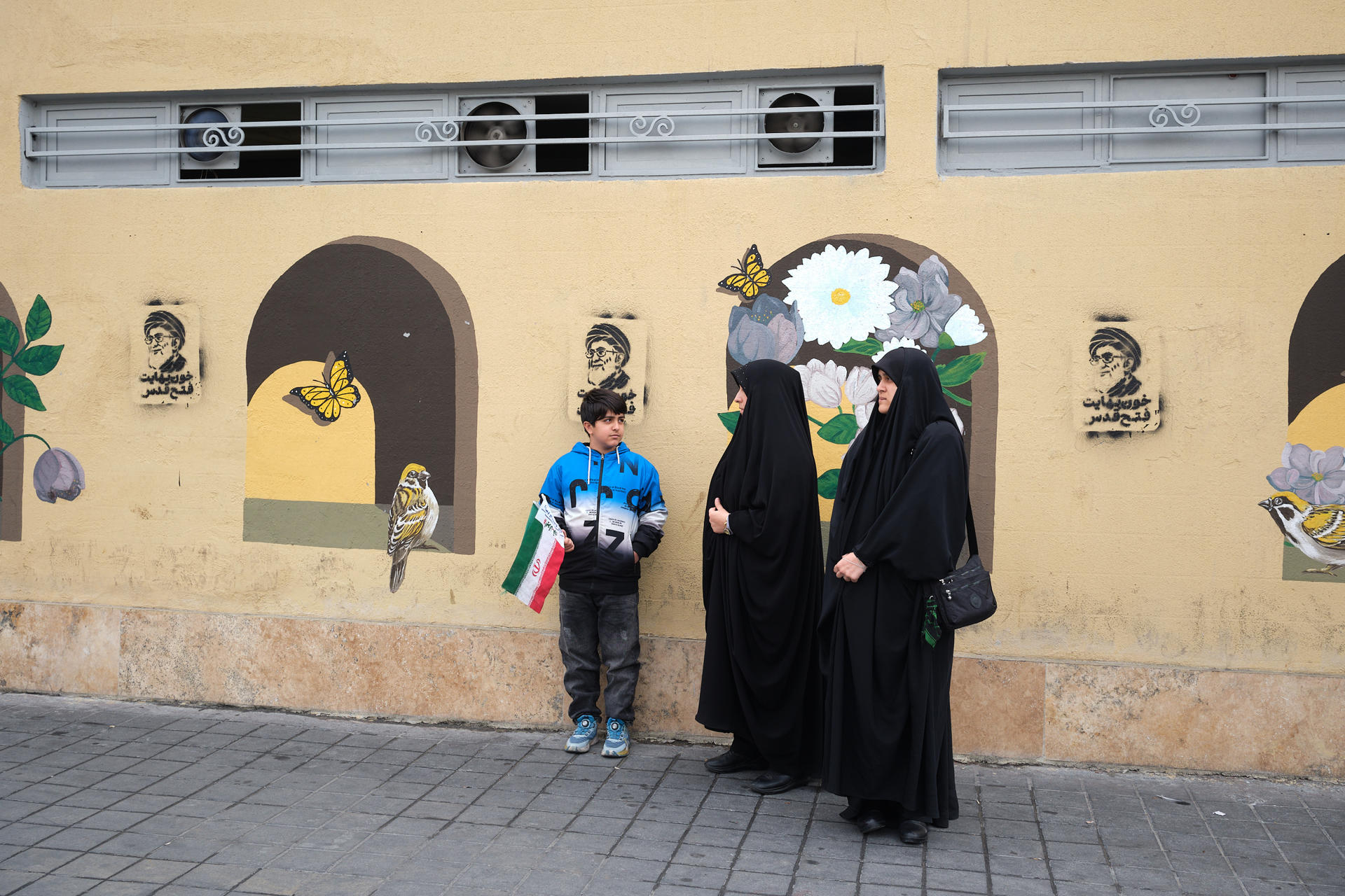 Un grupo de personas esperan frente a grafitis del asesinado líder supremo de Irán Alí Jameneí en las inmediaciones de la plaza Engelab (Revolución) de Teherán. Desde su muerte el 28 de febrero en ataques de Estados Unidos e Israel, las calles de Teherán se han llenado de grafitis, carteles y murales con su retrato. EFE/Jaime León