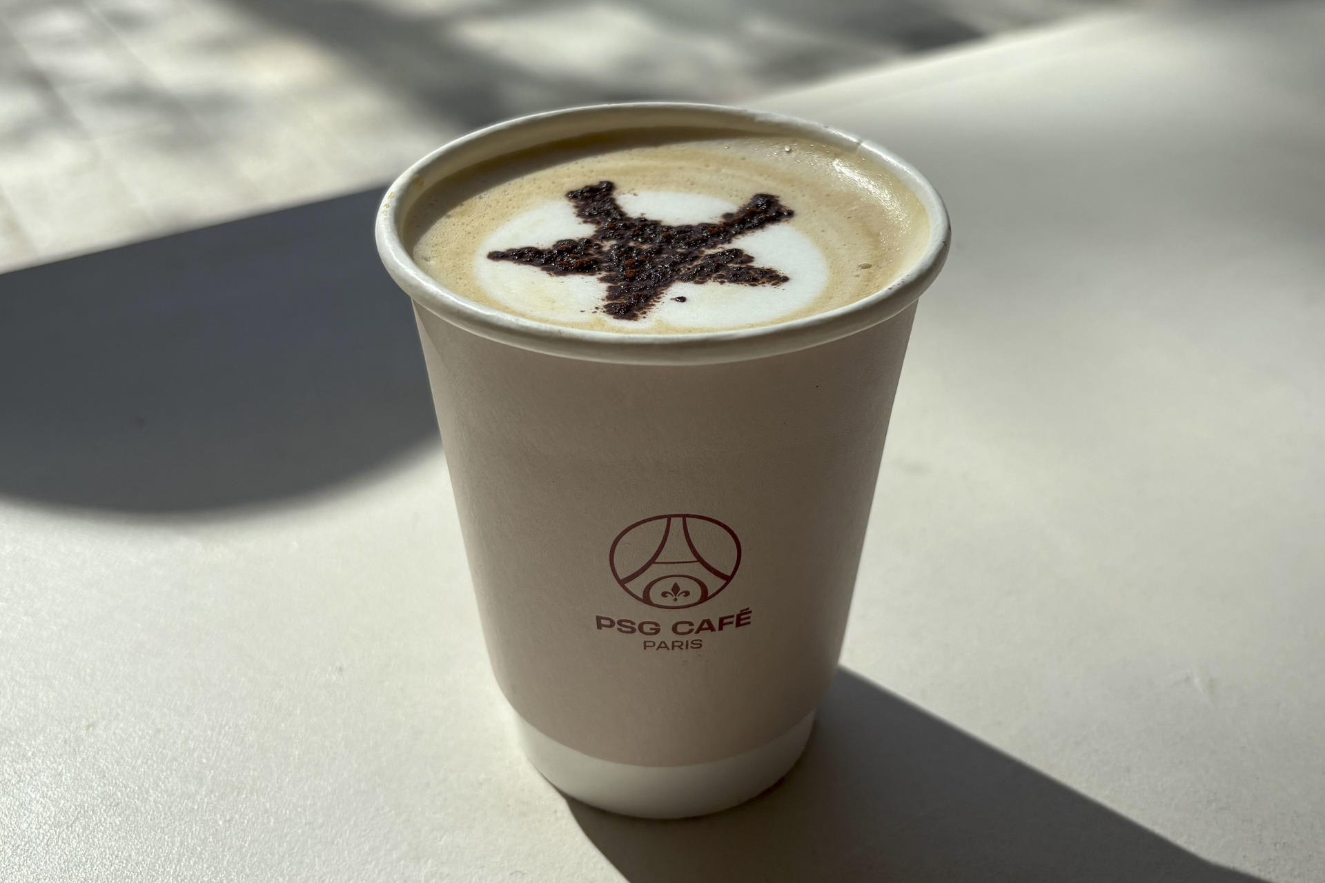 Café servido con la estrella del campeonato europeo en cacao. Magdalenas rellenas de frambuesas y 'capuccinos' con la Torre Eiffel dibujada en su espuma son los productos estrella del primer 'PSG Café', un establecimiento inaugurado recientemente en los Campos Elíseos de la capital francesa y que supone una nueva apuesta para extender la marca del club más allá del terreno de juego. EFE/ Pol Lloberas Cardona