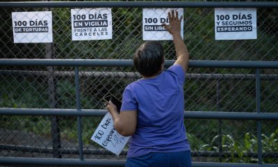Una persona pega carteles previo a una vigilia afuera de la cárcel El Rodeo I este sábado, en Guatire (Venezuela). EFE/ Ronald Peña R