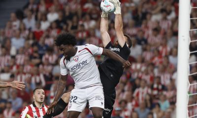 El guardameta del Athletic Unai Simón (d) salta por el balón con Flavien-Enzo Boyomo, de Osasuna, durante el encuentro correspondiente a la jornada 32 de LaLiga que disputaron Athletic Club y Osasuna este martes en el estadio de San Mamés, en Bilbao. EFE / Miguel Toña.