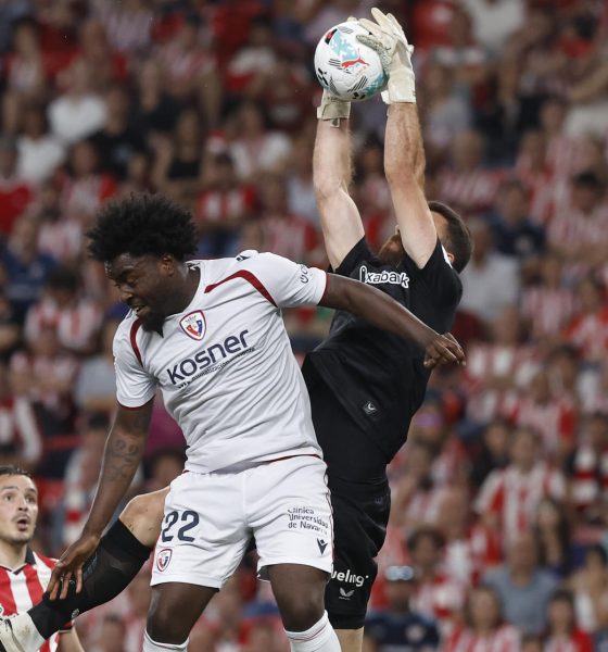El guardameta del Athletic Unai Simón (d) salta por el balón con Flavien-Enzo Boyomo, de Osasuna, durante el encuentro correspondiente a la jornada 32 de LaLiga que disputaron Athletic Club y Osasuna este martes en el estadio de San Mamés, en Bilbao. EFE / Miguel Toña.