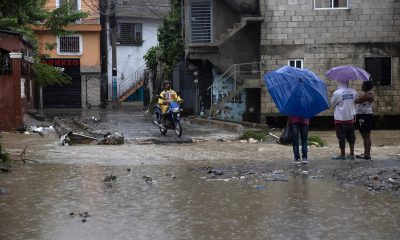 Personas cruzan una cañada desbordada en el barrio Manoguayabo, en Santo Domingo (República Dominicana). Imagen de archivo. EFE/Orlando Barría