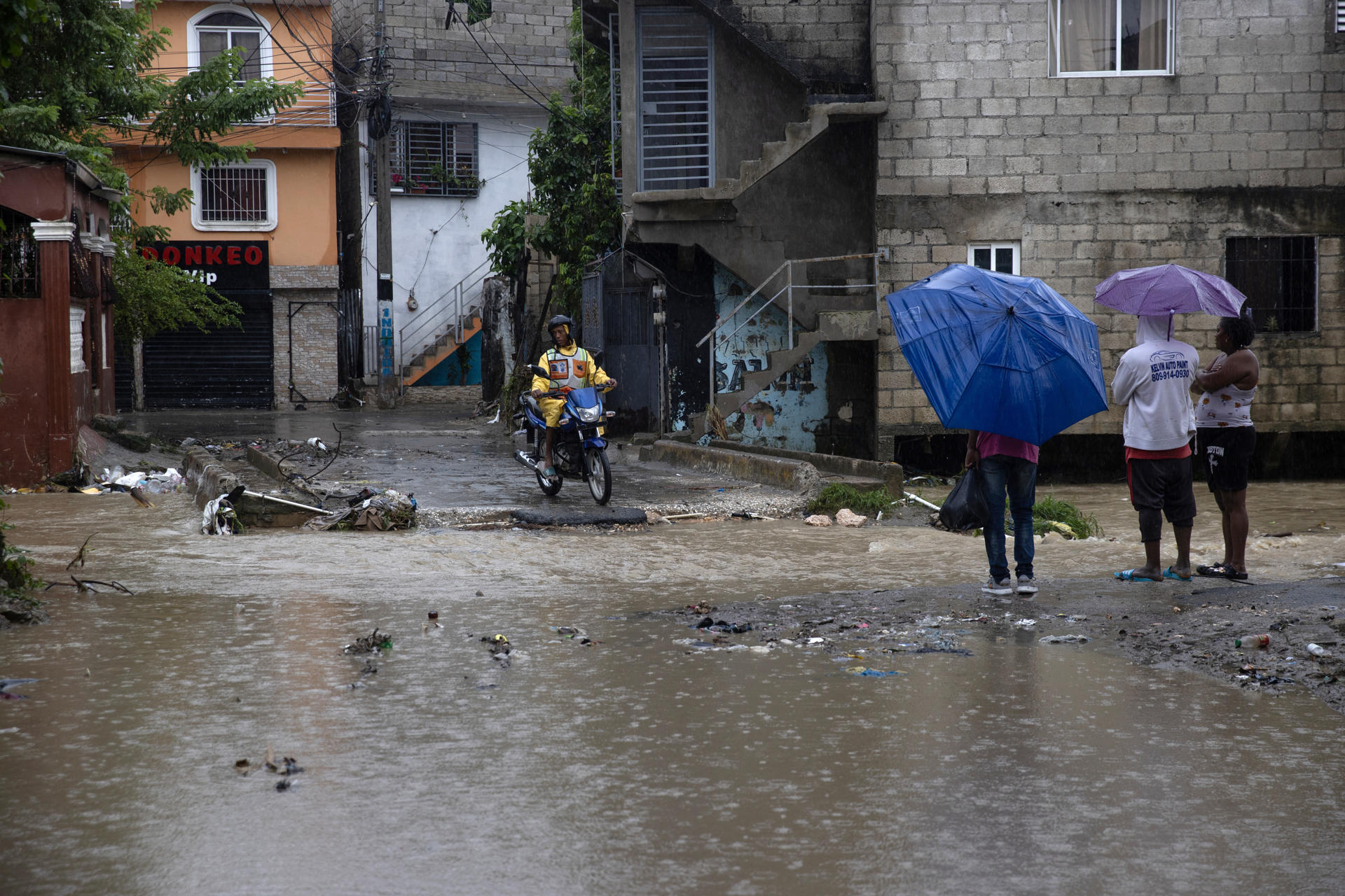 Personas cruzan una cañada desbordada en el barrio Manoguayabo, en Santo Domingo (República Dominicana). Imagen de archivo. EFE/Orlando Barría