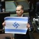 El diputado del partido polaco de extrema derecha Confederación, Konrad Berkowicz, muestra una bandera israelí marcada con una esvástica en el Parlamento polaco en Varsovia, Polonia, el pasado 14 de abril de 2026, cuando acusó a Israel de ser el "nuevo Tercer Reich" y de cometer un genocidio en Gaza. (Polonia, Varsovia) EFE/EPA/RAFAL GUZ POLONIA FUERA