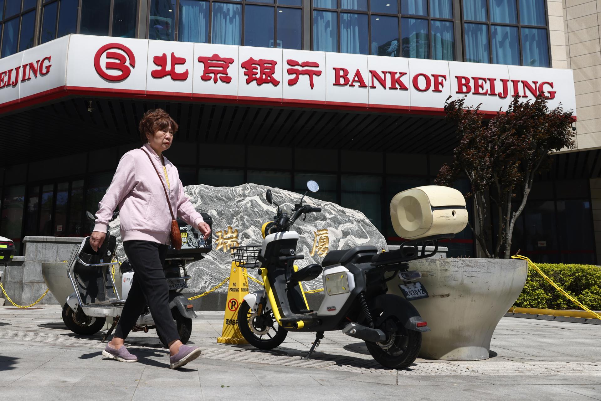 Fotografía tomada el 20/04/2026, que muestra a una mujer caminando frente a una oficina del Banco de Pekín, en China. EFE/EPA/WU HAO