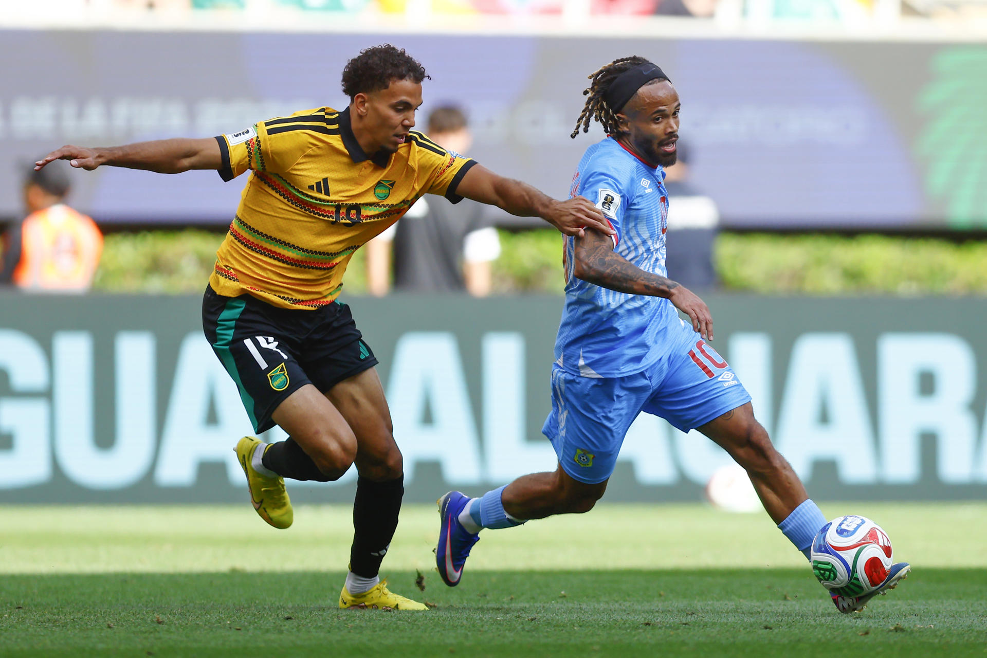 Theo Bongonda (d), de Congo, disputa el balón con Isaac Hayden, de Jamaica, en un partido de repechaje para el Mundial 2026 entre República Democrática del Congo y Jamaica en el Estadio Akron en Guadalajara (México). EFE/Francisco Guasco