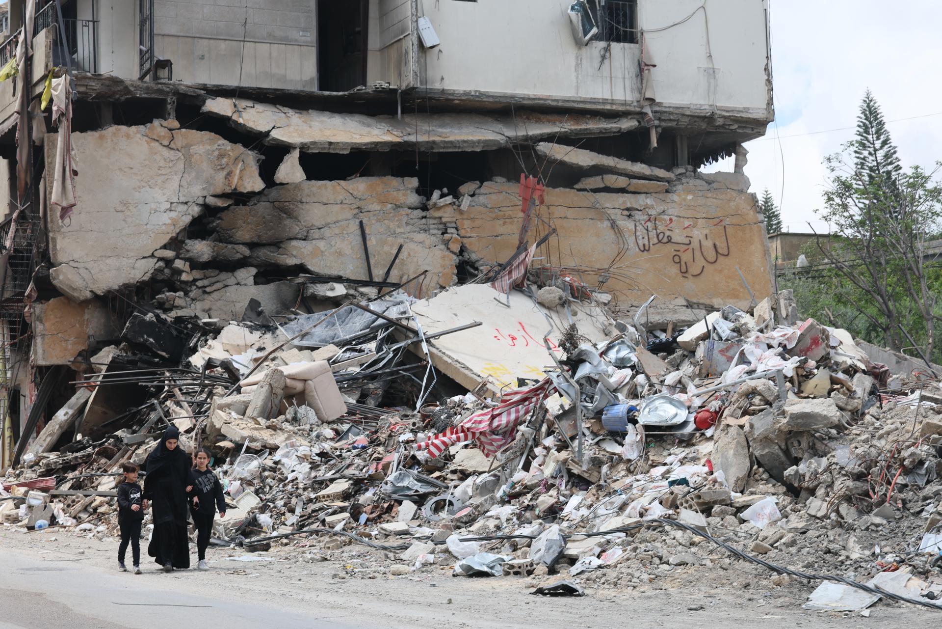 Personas caminan junto a los escombros de un edificio dañado por un ataque aéreo israelí en la aldea de Jibchit, al sur del Líbano, el 21 de abril de 2026. EFE/EPA/WAEL HAMZEH