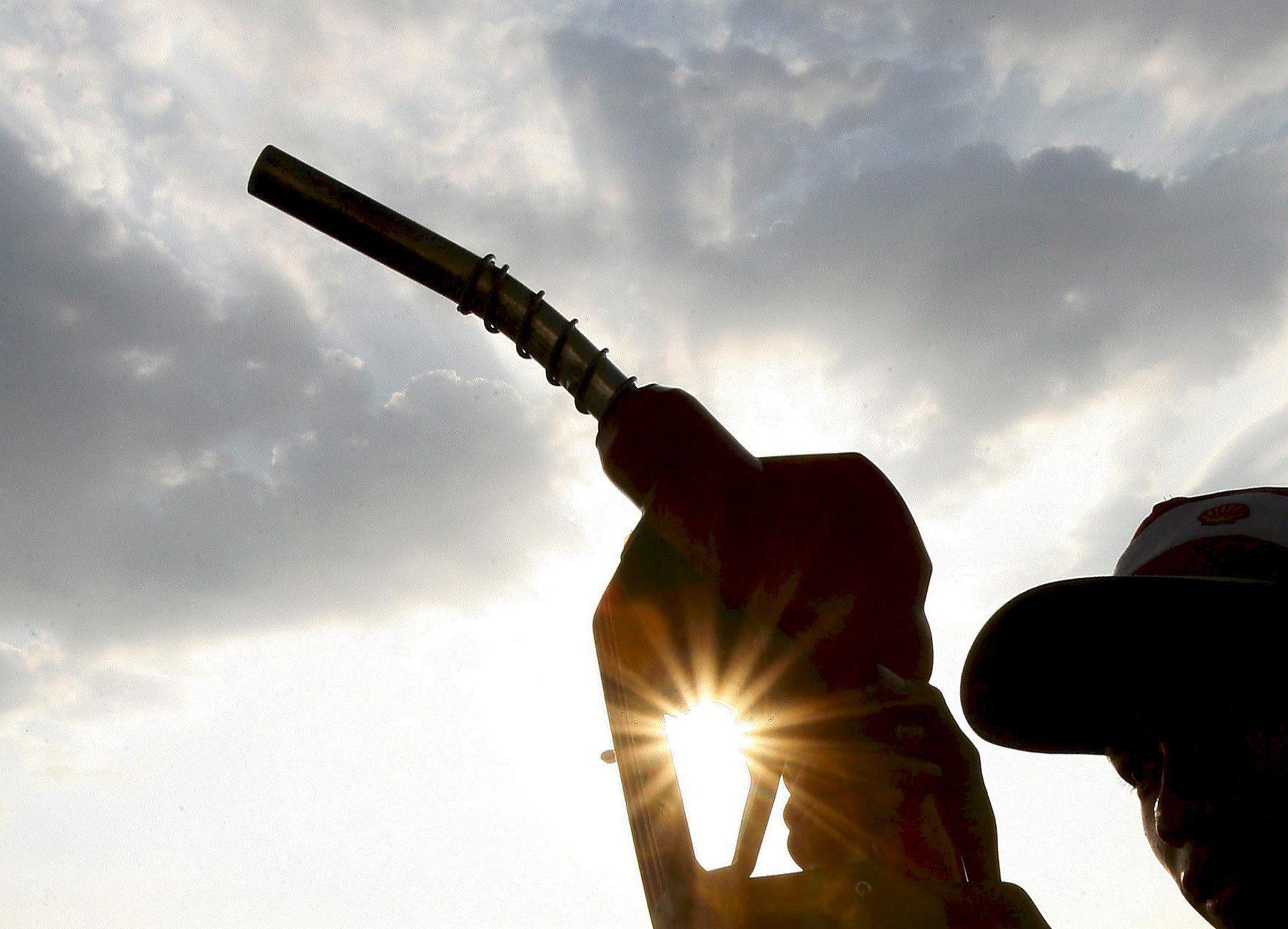 Imagen de un hombre con la manguera de un surtidor de una gasolinera. EFE/Francis R. Malasig