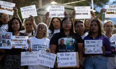 Personas sostienen carteles durante una vigilia afuera de la cárcel El Rodeo I este sábado, en Guatire (Venezuela). EFE/ Ronald Peña R
