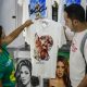 Un par de turistas fue captado el pasado 29 de abril al detallar una camiseta con la imagen de la artista Shakira, antes del espectáculo gratuito que ofrecerá la colombiana en las playas de Copacabana, en Río de Janeiro (Brasil). EFE/Antonio Lacerda