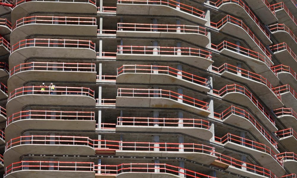 Dos empleados de la construcción permanecen en uno de los balcones de la Grand Tower, el edificio residencial más alto de Alemania, en Fráncfort, en una imagen de archivo. EFE/ Mauritz Antin