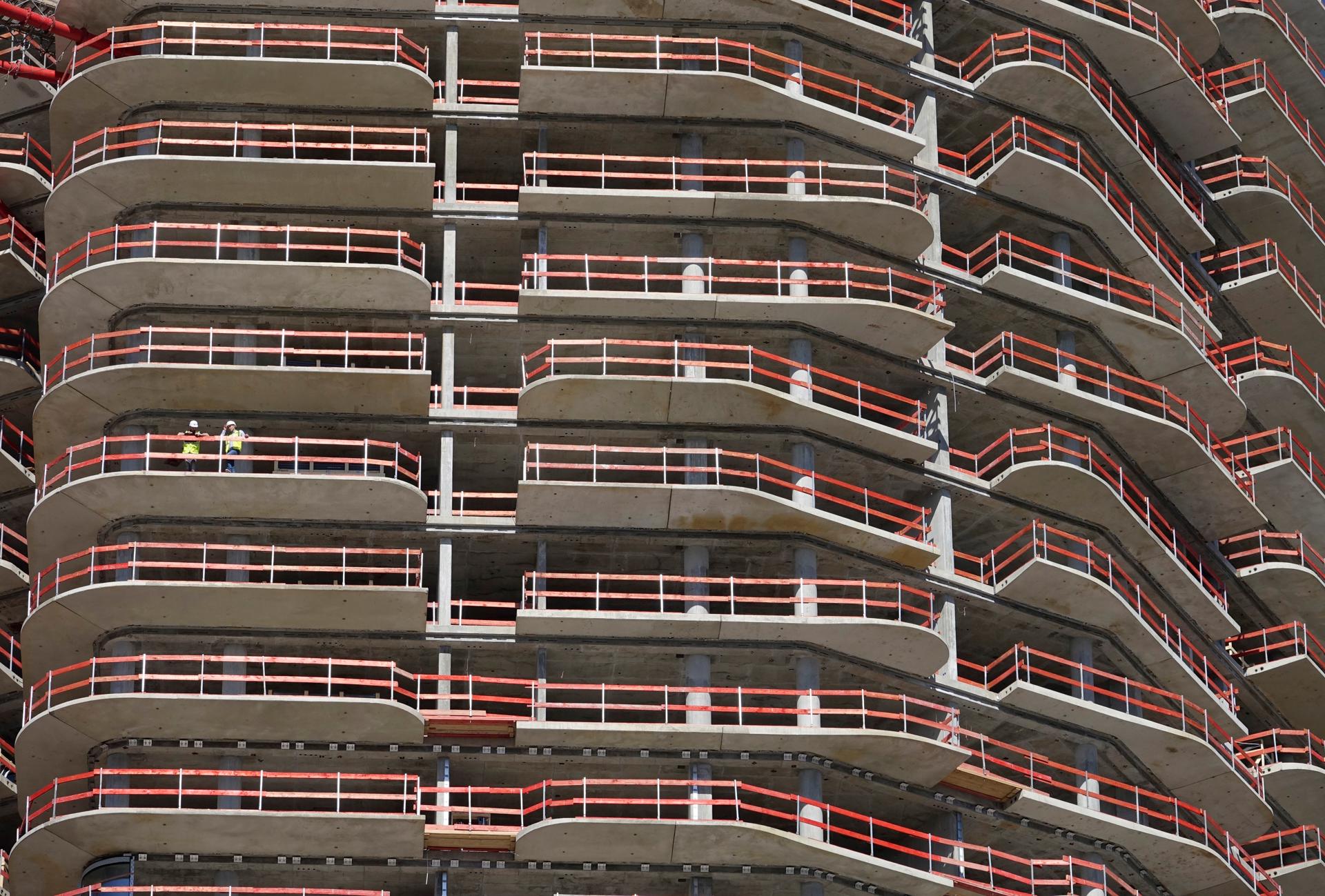 Dos empleados de la construcción permanecen en uno de los balcones de la Grand Tower, el edificio residencial más alto de Alemania, en Fráncfort, en una imagen de archivo. EFE/ Mauritz Antin