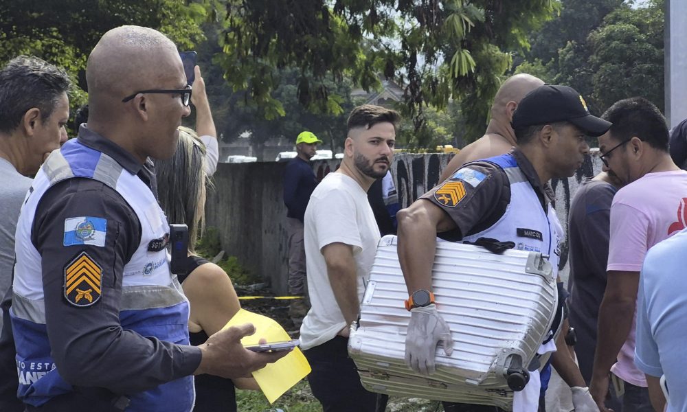 Fotografía cedida este domingo por Roberta Durço que muestra a un policía militar transportando una maleta recuperada en el lugar donde ocurrió el accidente de dos helicópteros en el barrio Recreio dos Bandeirantes, en Río de Janeiro (Brasil). EFE/ Roberta Durço