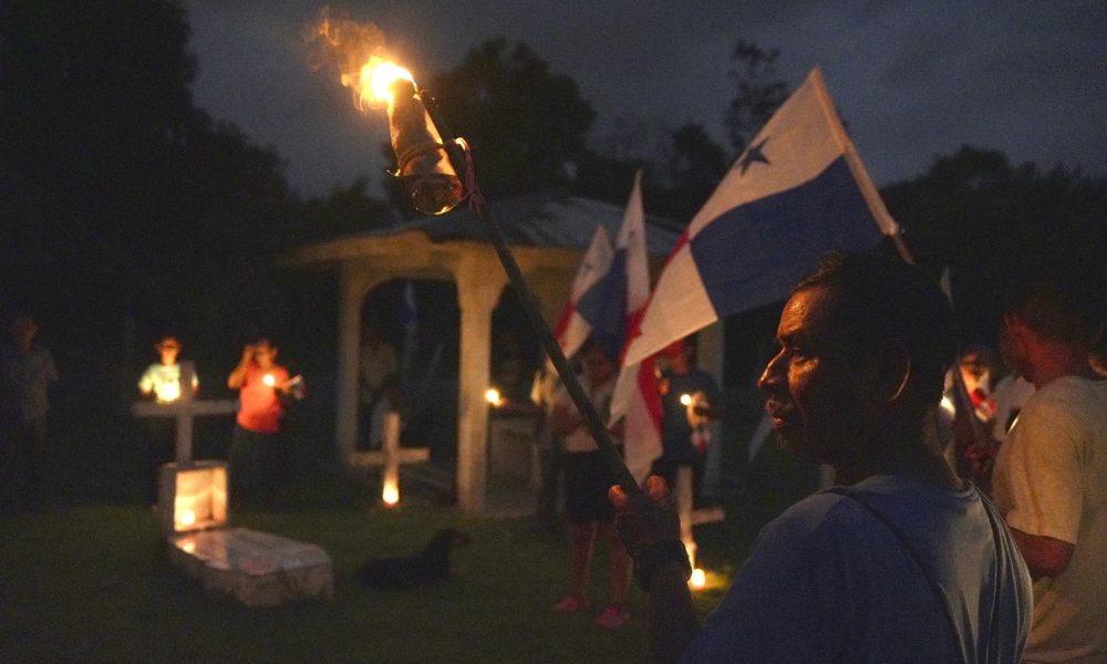 Campesinos sostienen banderas y velas en una vigilia en rechazo al decreto ejecutivo que ordena la clausura de los cementerios comunitarios para dar paso a la construcción del embalse de Río Indio, proyecto impulsado por el Canal de Panamá en la comunidad de Limón de Chagres (Panamá). EFE/Aris Mariota