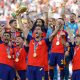 El español Mikel Merino levanta el trofeo de la Copa del Mundo mientras el equipo celebra tras ganar la final de la Copa Mundial de la FIFA 2026. EFE/EPA/CHRISTOPHER NEUNDORF