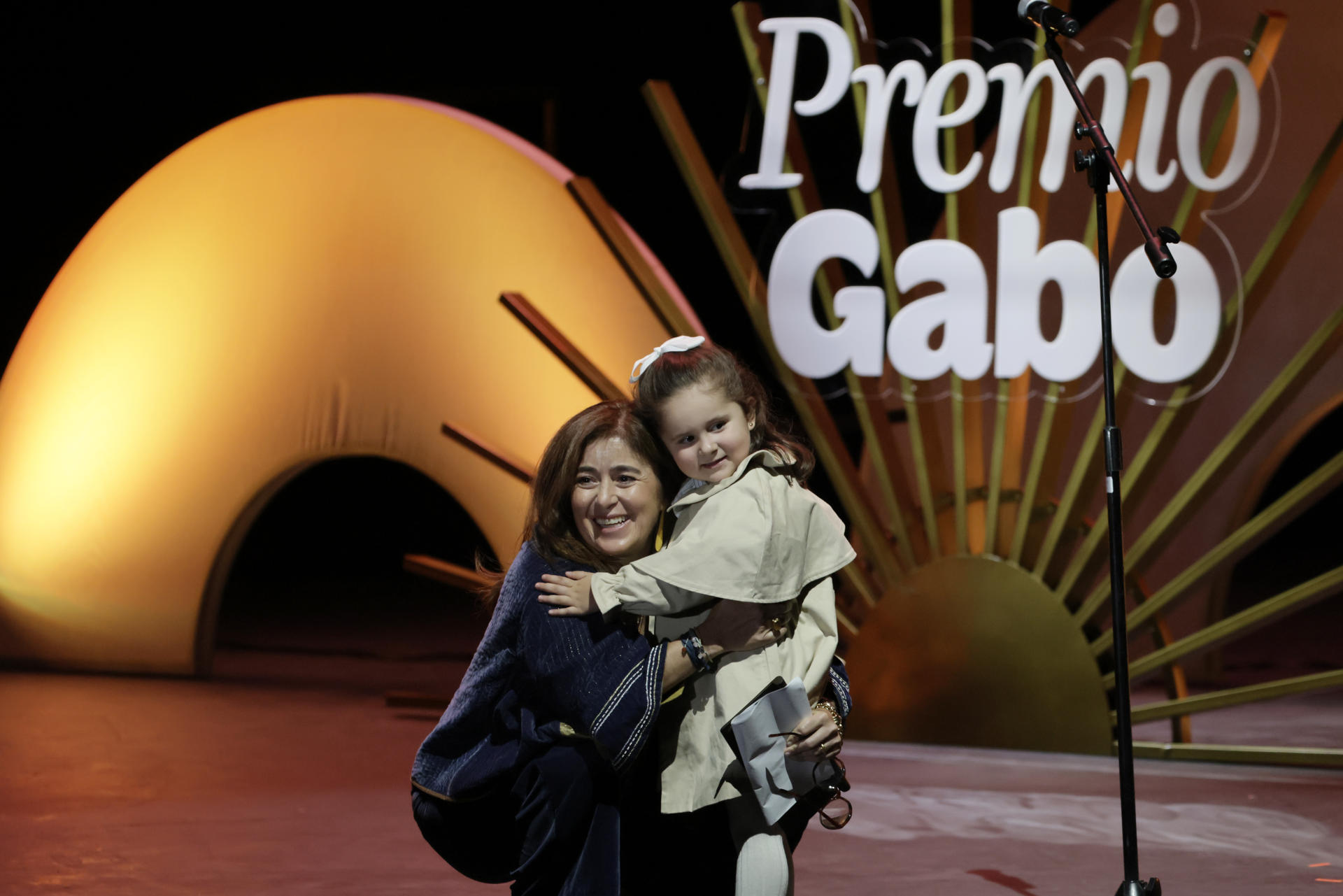 La periodista colombiana Catalina Gómez Ángel abraza a una niña luego de recibir el Reconocimiento a la Excelencia del Premio Gabo 2026 este viernes, en el Teatro Municipal Jorge Eliécer Gaitán, en Bogotá (Colombia). EFE/ Carlos Ortega
