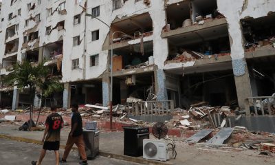 Personas caminan este sábado frente a edificios afectados por los terremotos ocurridos en la zona de Caraballeda, en La Guaira (Venezuela). EFE/ Raúl Martínez