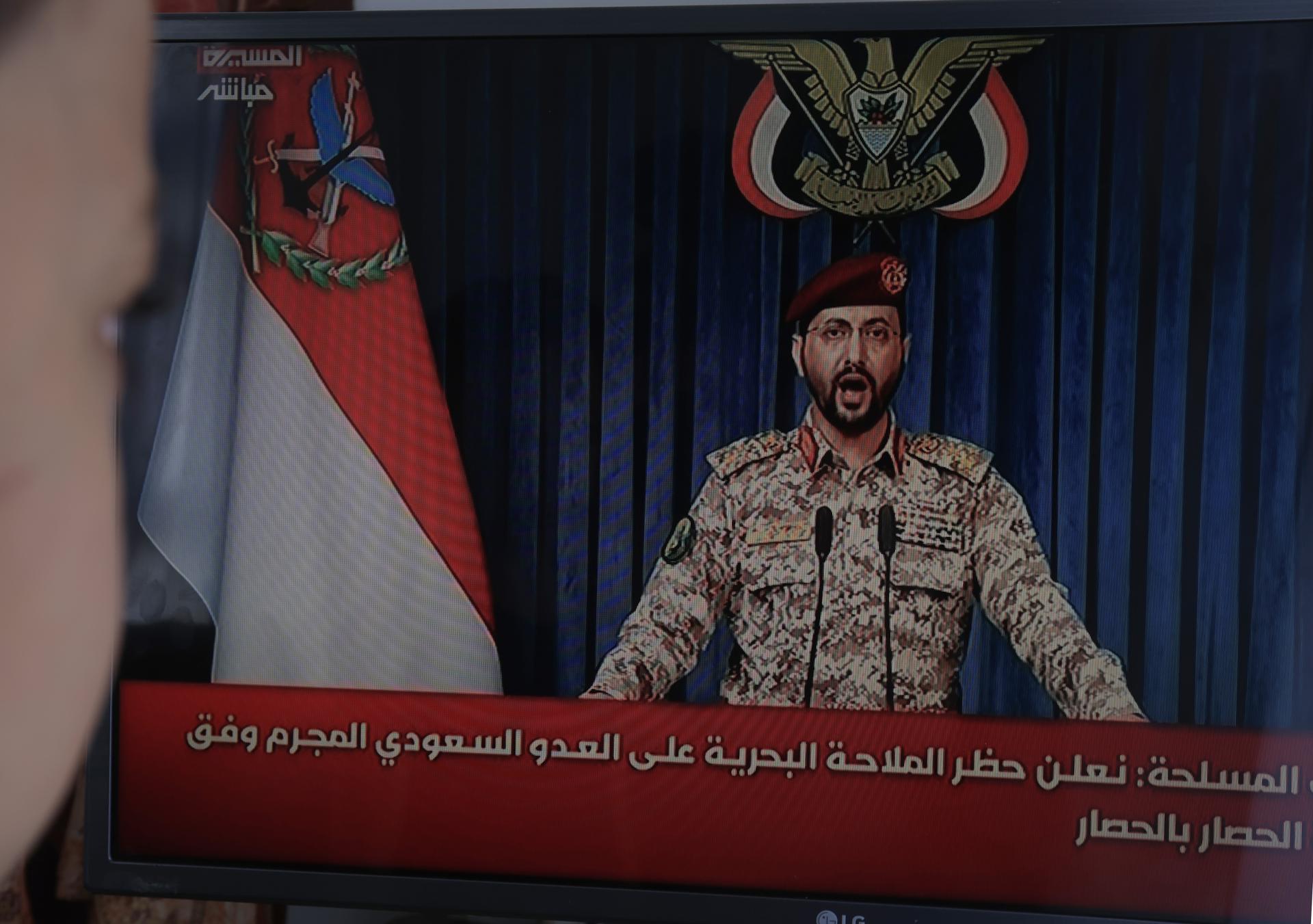 Una persona observa al portavoz militar hutí, Yahya Sarea, pronunciar un comunicado televisado en Saná, Yemen, este lunes. EFE/EPA/YAHYA ARHAB