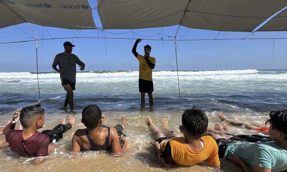 Bajo toldos improvisados con lonas de Unicef, más de una treintena de niños se zambullen en el mar en Gaza y aprenden a flotar acompañados de un grupo de monitores. EFE/Str