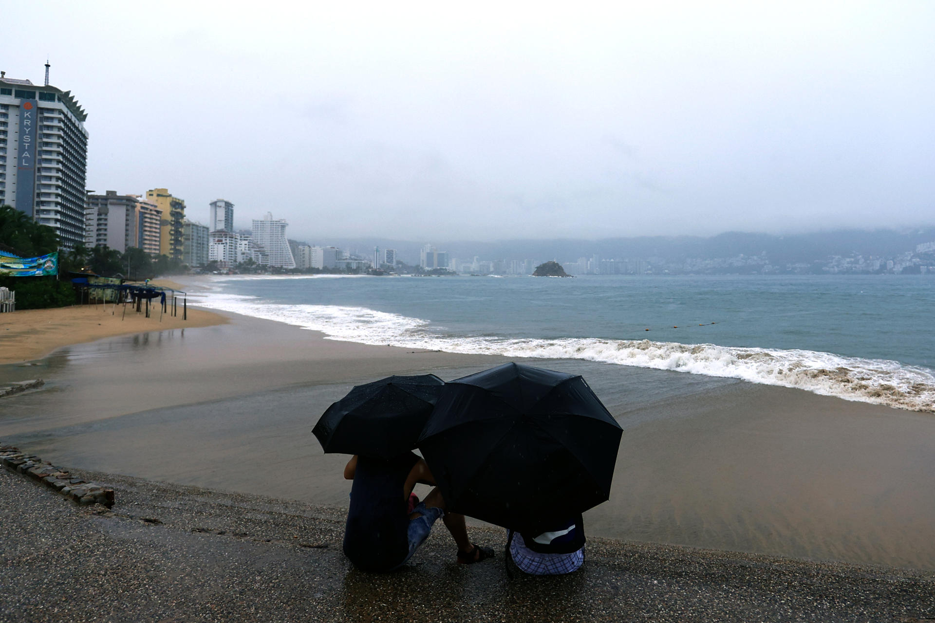 Personas se protegen de la lluvia en Acapulco (México). Fotografía de archivo. EFE/David Guzmán