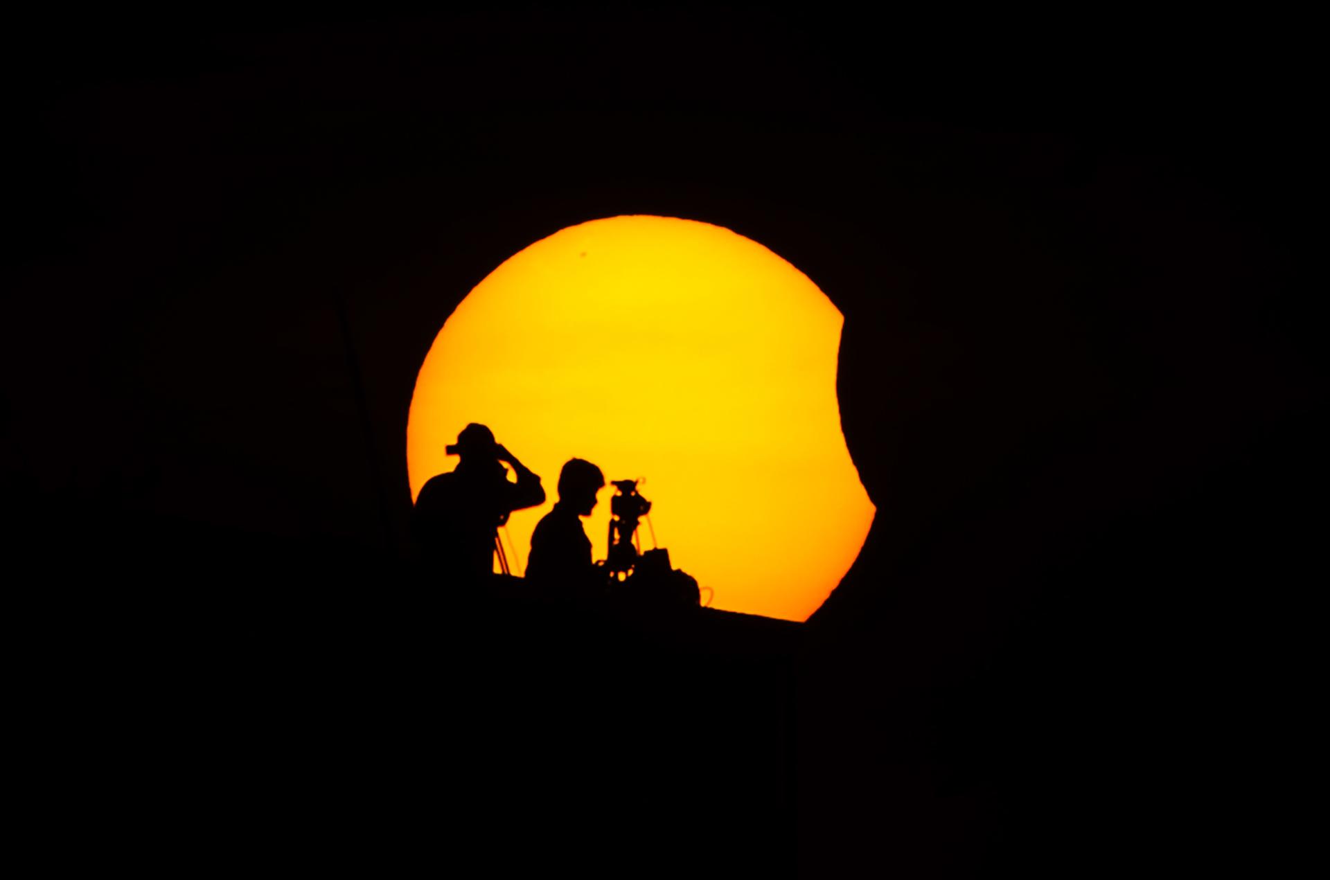 Fotografía de archivo en la que se captó la silueta de un par de camarógrafos al registrar el inicio de un eclipse total de sol, en Chennai (India). EFE/Idrees Mohammed