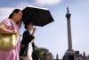 Unas personas utilizan un paraguas para protegerse del sol mientras visitan Trafalgar Square, en el centro de Londres (Reino Unido). EFE/EPA/TOLGA AKMEN
